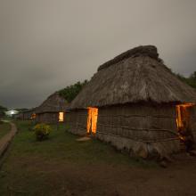 Night time shot of a traditional Fijian bure or homes made with thatched roofs and natural material walls.